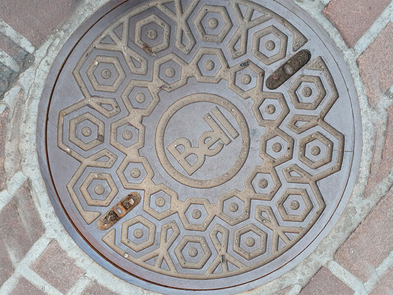 Дизайнерский чугунный люк с логотипом компании Bell